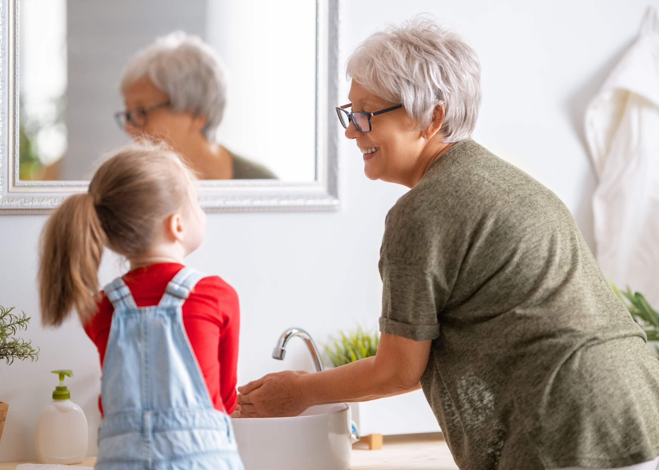 girl and her grandmother are washing hands|